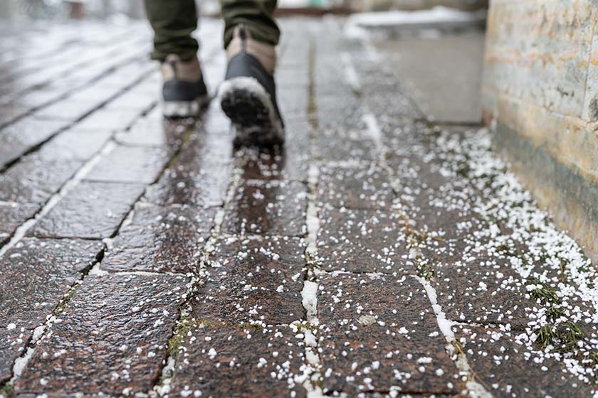 A person walks over a snowy paver pathway.